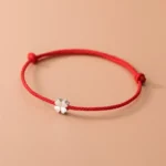 925 sterling silver four leaf clover red string bracelet flat lay view on beige background
