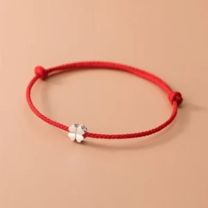 925 sterling silver four leaf clover red string bracelet flat lay view on beige background