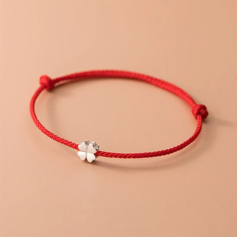 925 sterling silver four leaf clover red string bracelet flat lay view on beige background