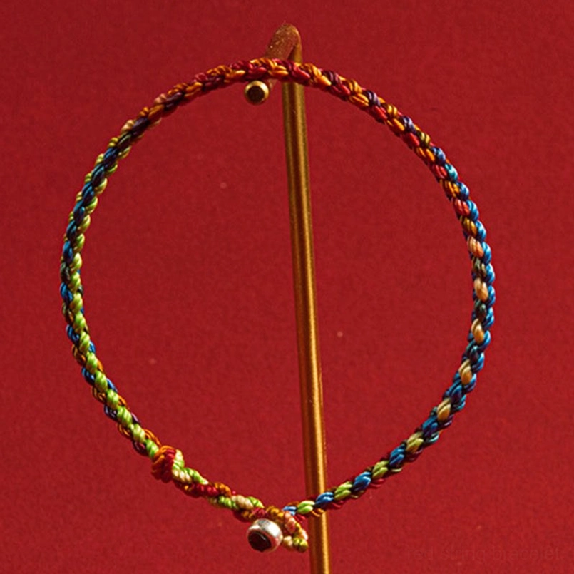 Red string protection bracelet metal bell fastener twisted braided rope side view