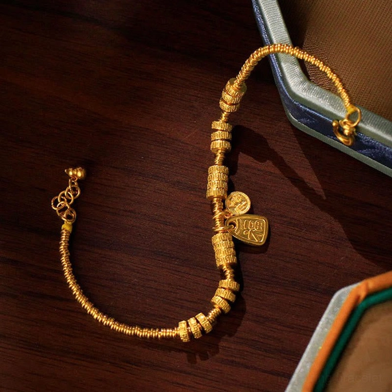 Close-up oblique view of adjustable gold Fu bracelet with engraved details and pendants