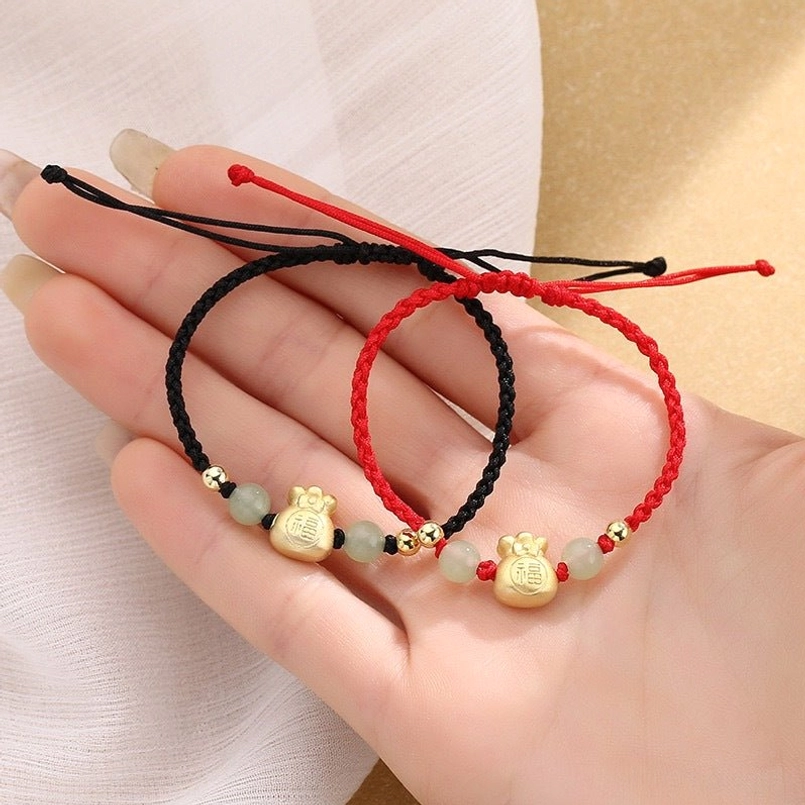 Two lucky braided bracelets red and black styles held in palm hand display
