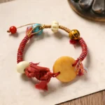 Red string bracelet with Fu character bone charm and colorful beads flat lay on wooden surface