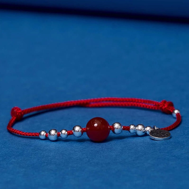 Sterling silver Fu character red agate bracelet displayed on blue fabric background