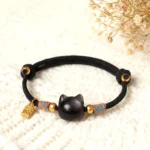Silver Sheen Obsidian cat protection bracelet with Fu character charm on knitted blanket with dried flowers