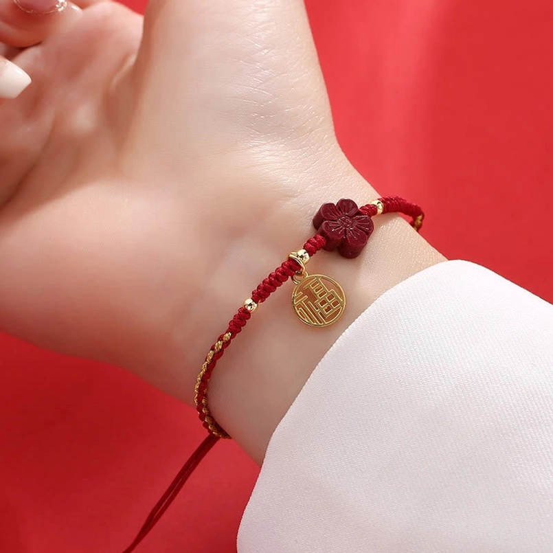 Dual-tone braided cinnabar Fu bracelet with gold pendant on wrist