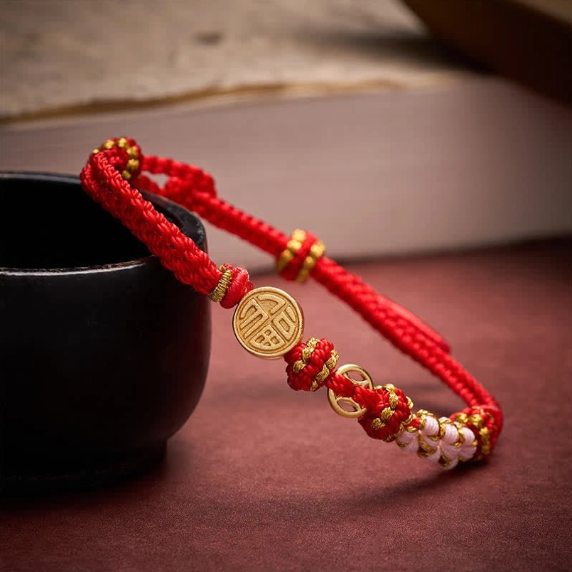 Fu character copper charm red string blessing bracelet side view on tabletop