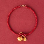 Fu character red string bracelet with gold bell charm - overhead flat lay view