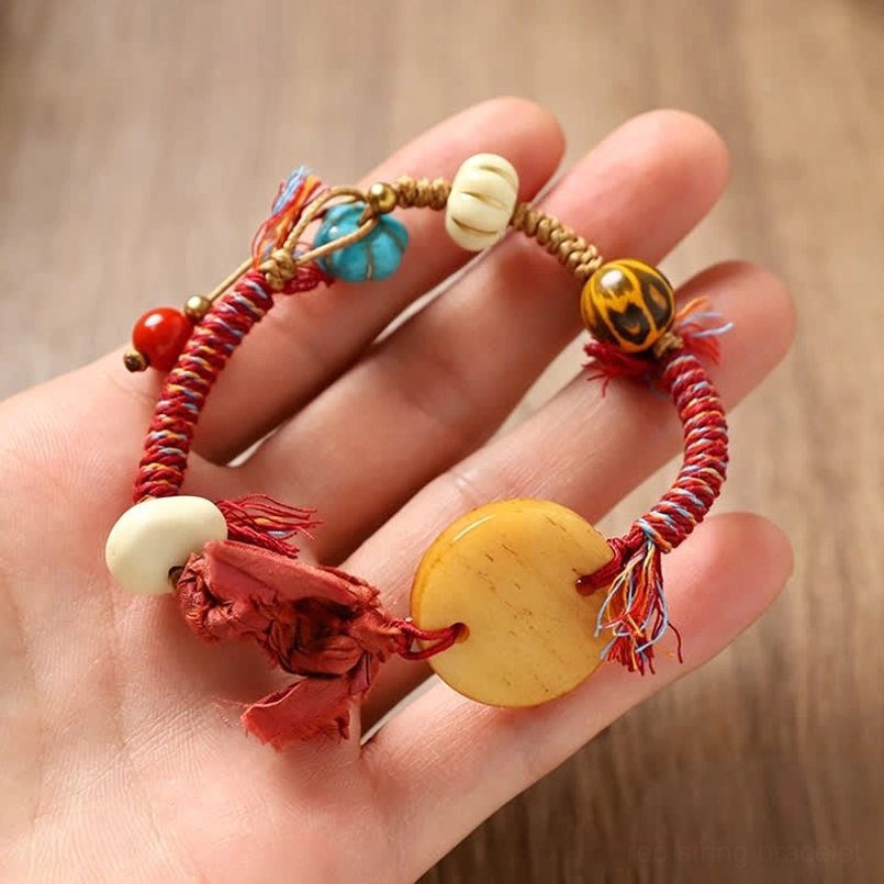 Red braided rope bracelet with Fu charm worn on hand showing adjustable fit and detail
