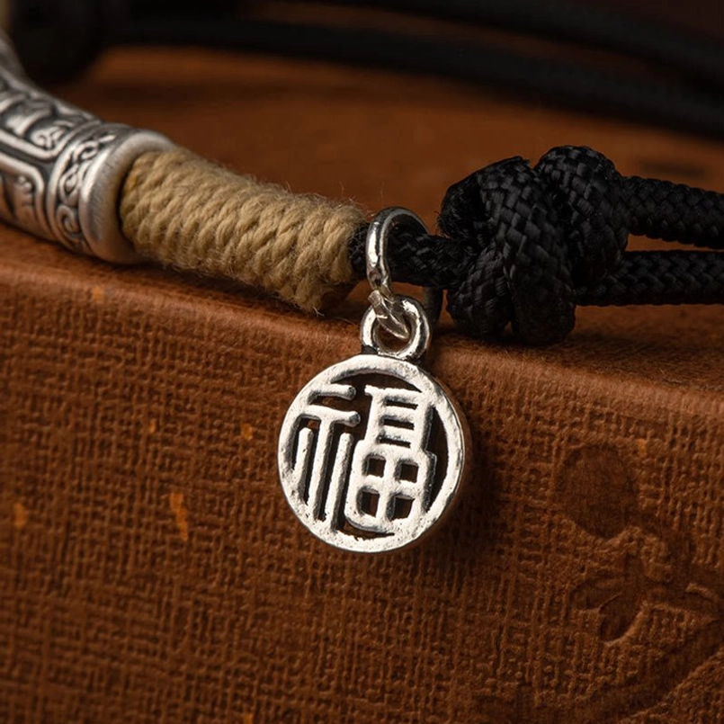 close-up macro of round fu character silver pendant on black braided knot cord