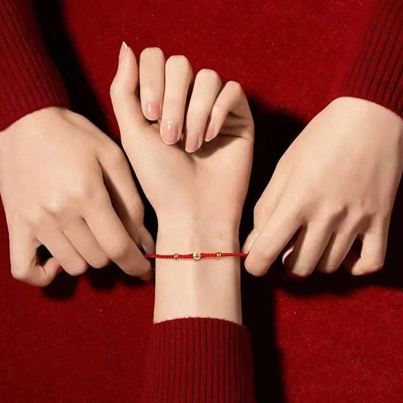 Red string Fu charm bracelet close up detail of silver charm engraving