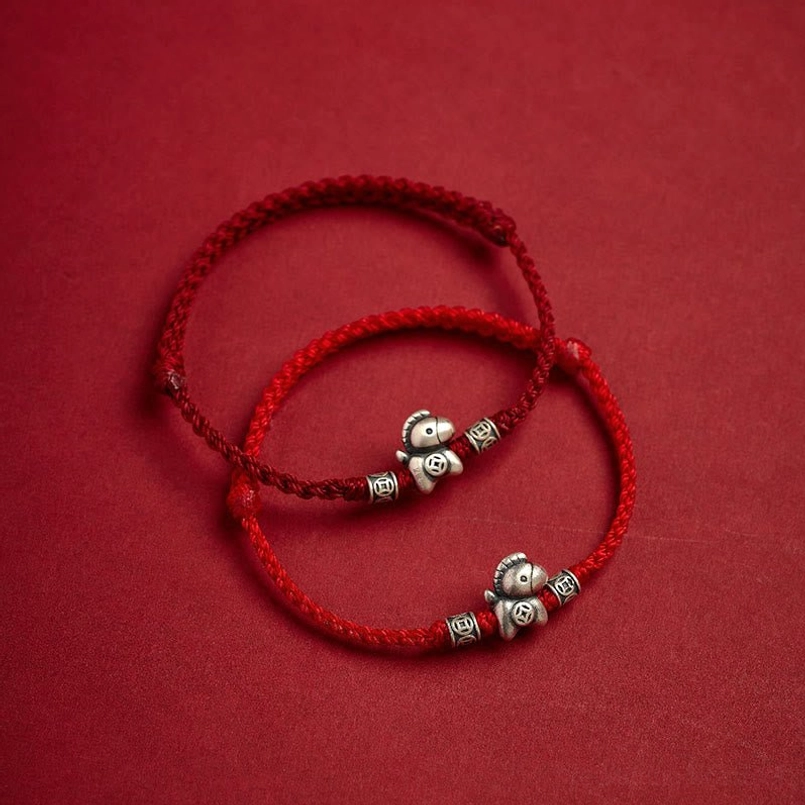 Fu character silver charm closeup on red string bracelet