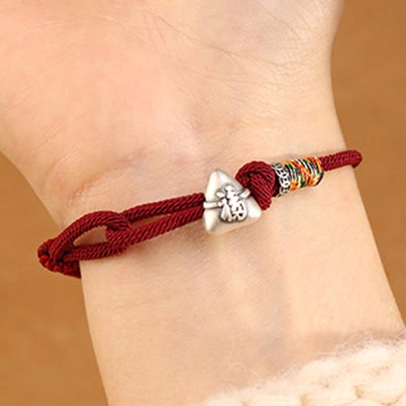 Alternative angle of fu zongzi red string bracelet worn on wrist with sweater