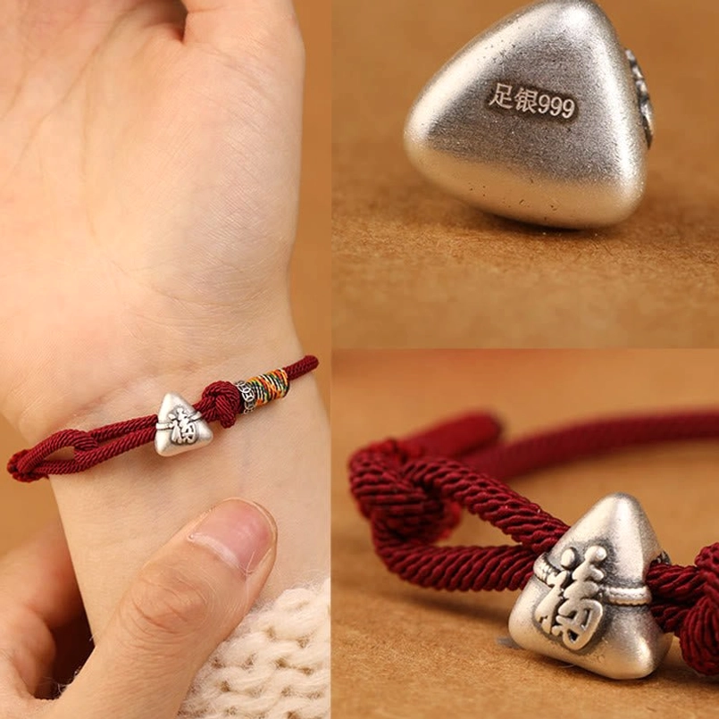 Fu zongzi red string bracelet detail shot showing braided cord and silver charm