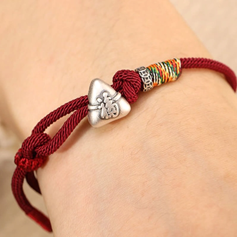 Close up fu zongzi red string bracelet worn on bare wrist showing details