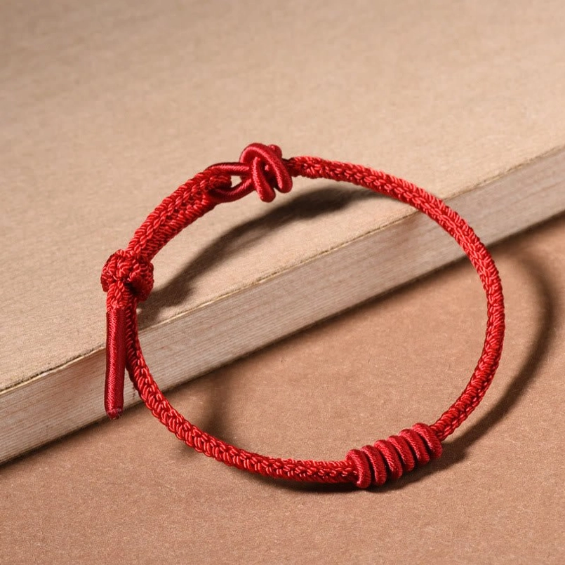 Eight stranded red string bracelet full view on wooden neutral background