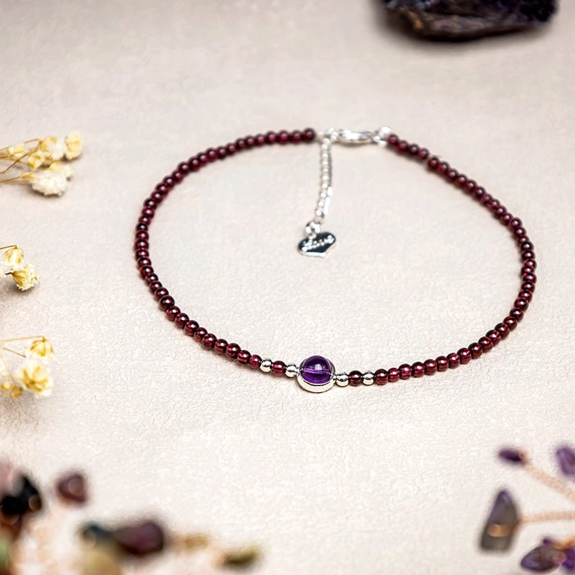 Garnet amethyst red string anklet flat lay with dried flowers and crystal props