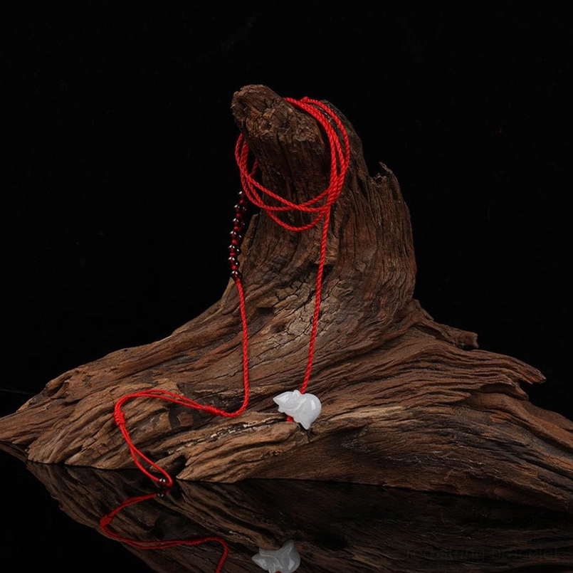 Red string belly chain wrapped on natural driftwood, featuring garnet beads and jade details