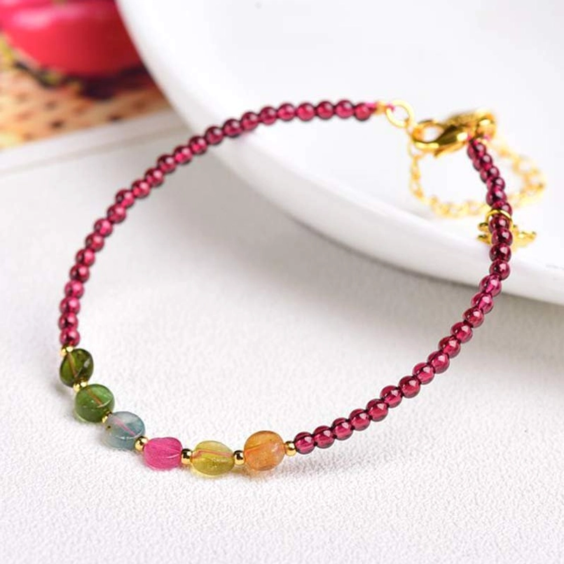 Garnet tourmaline protection bracelet with burgundy garnet beads and gold clasp on white plate