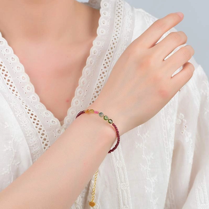 Garnet tourmaline bracelet worn on woman's wrist with gold extension chain