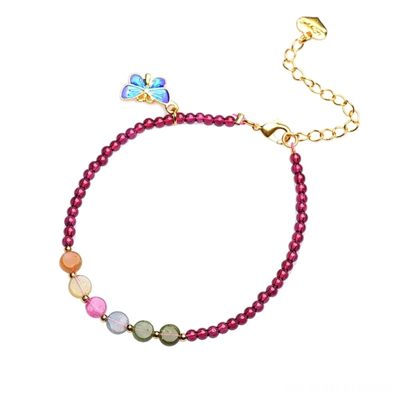 Garnet tourmaline butterfly bracelet on wooden table with blue enamel charm