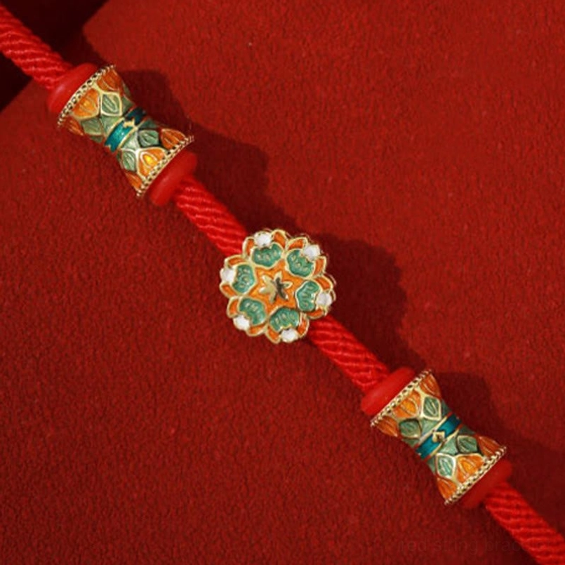 Angled top down view of gem studded lotus charm red string bracelet Dunhuang style