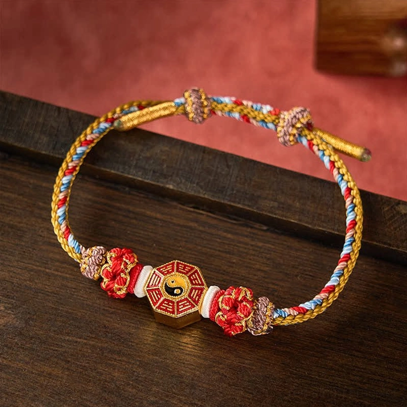 Gold and multicolor Bagua bracelet red string wooden background detail view