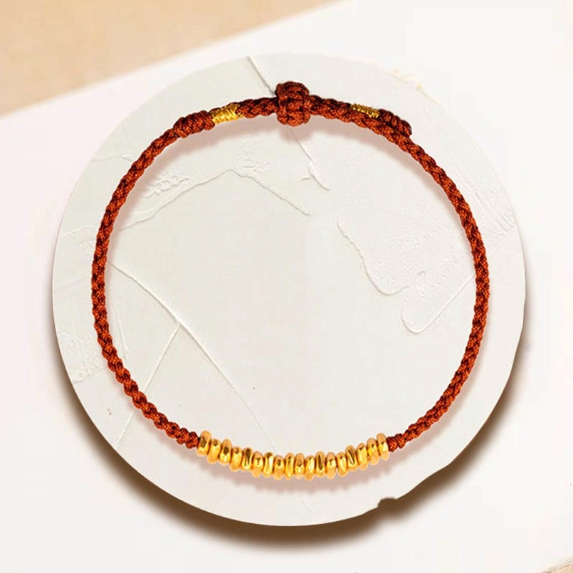 red braided red string bracelet with 999 gold beads on white ceramic tray
