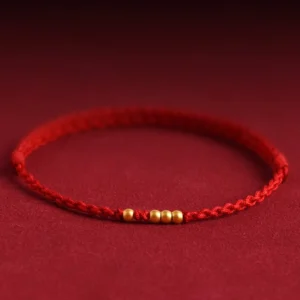 999 gold beads red string couple bracelet with adjustable knot, three-quarter view showing five matte gold beads on burgundy backdrop