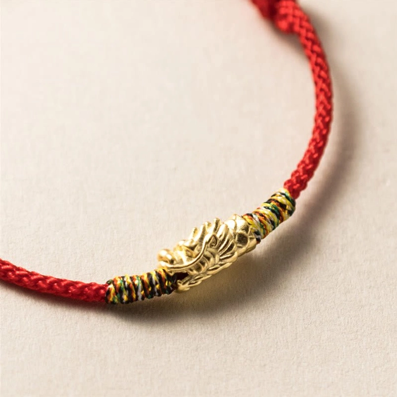 Gold dragon head red string bracelet with braided rope and colorful decorative wraps close-up