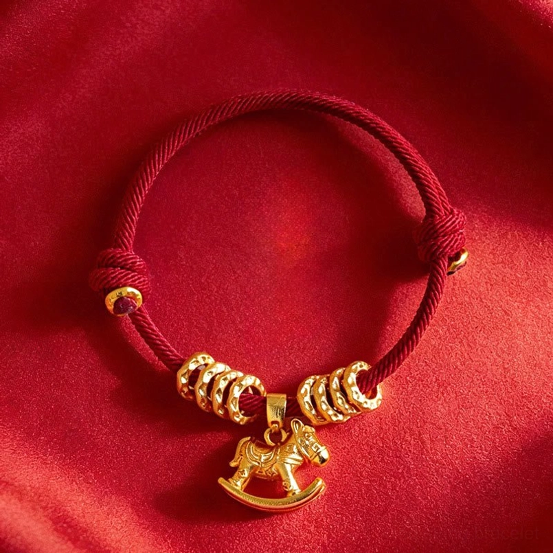 Detailed close up of gold horse circle charm on red string lucky bracelet