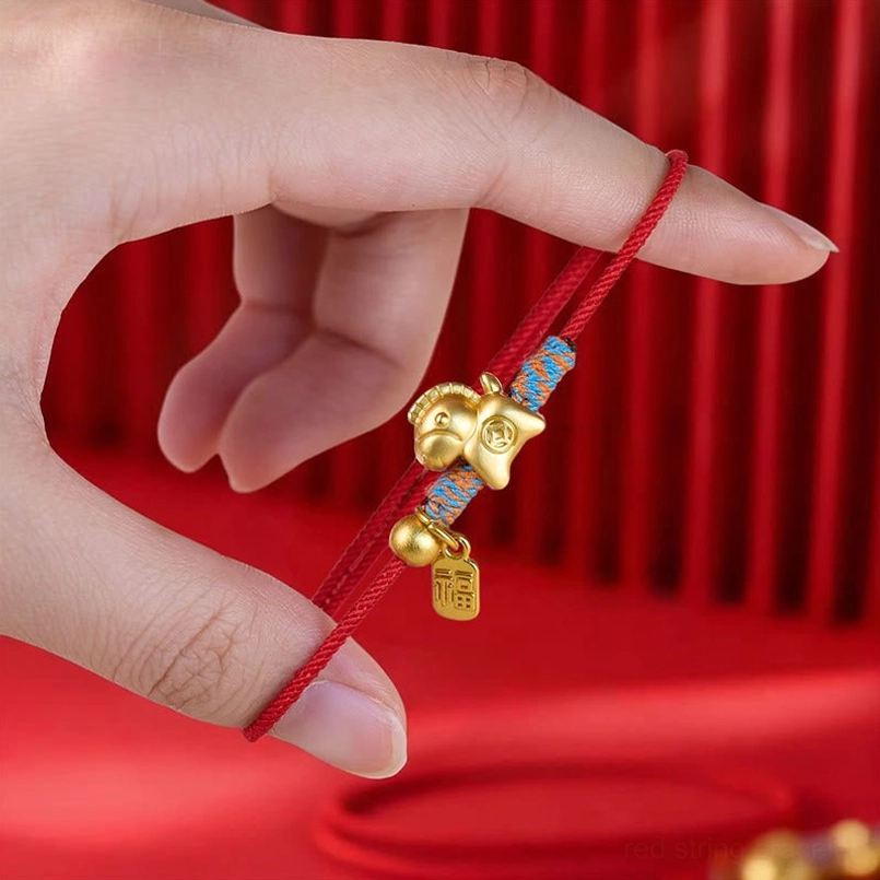 Close up view of gold horse and Fu tag pendant red string bracelet