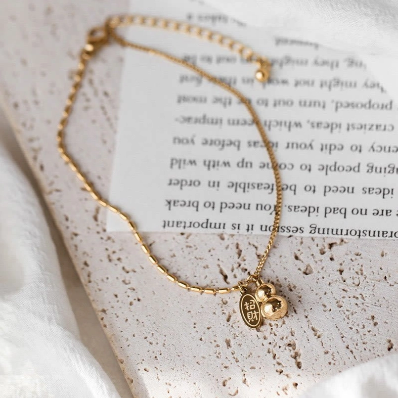 Flat lay view of lucky gourd wealth anklet with beaded chain and dangle pendants