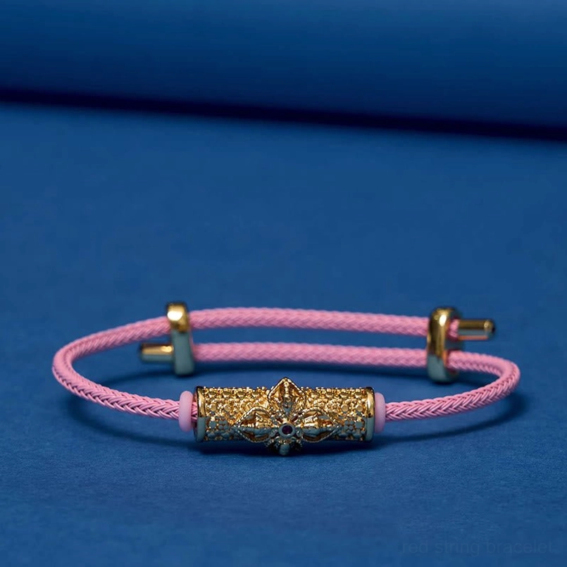Gold pink string luck bracelet showing handmade copper flower charm detail