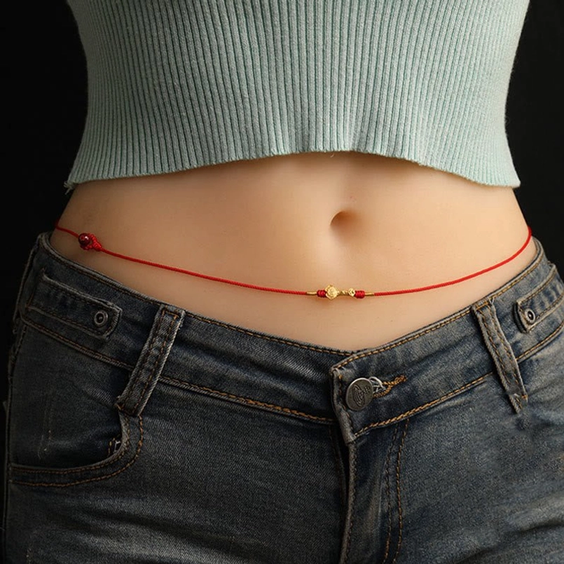 Red string belly chain side profile on woman, showing slim premium cord with central gold zodiac charm