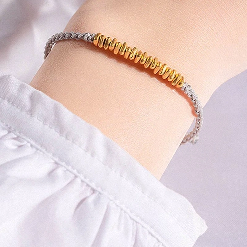 999 gold red string bracelet on terracotta background top view