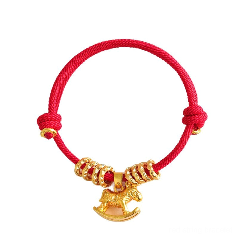 Gold rocking horse charm red string bracelet flat lay top view on white background