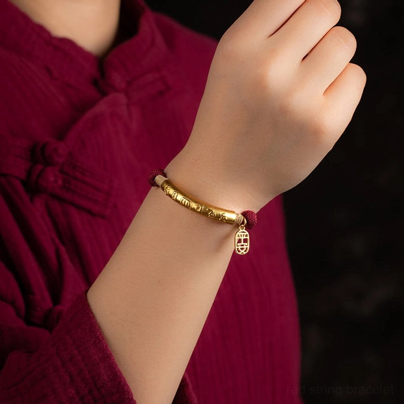 gold engraved om mani padme hum bracelet worn on wrist with traditional chinese style clothing