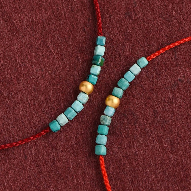 Close-up of turquoise square beads and gold round beads on braided red cord