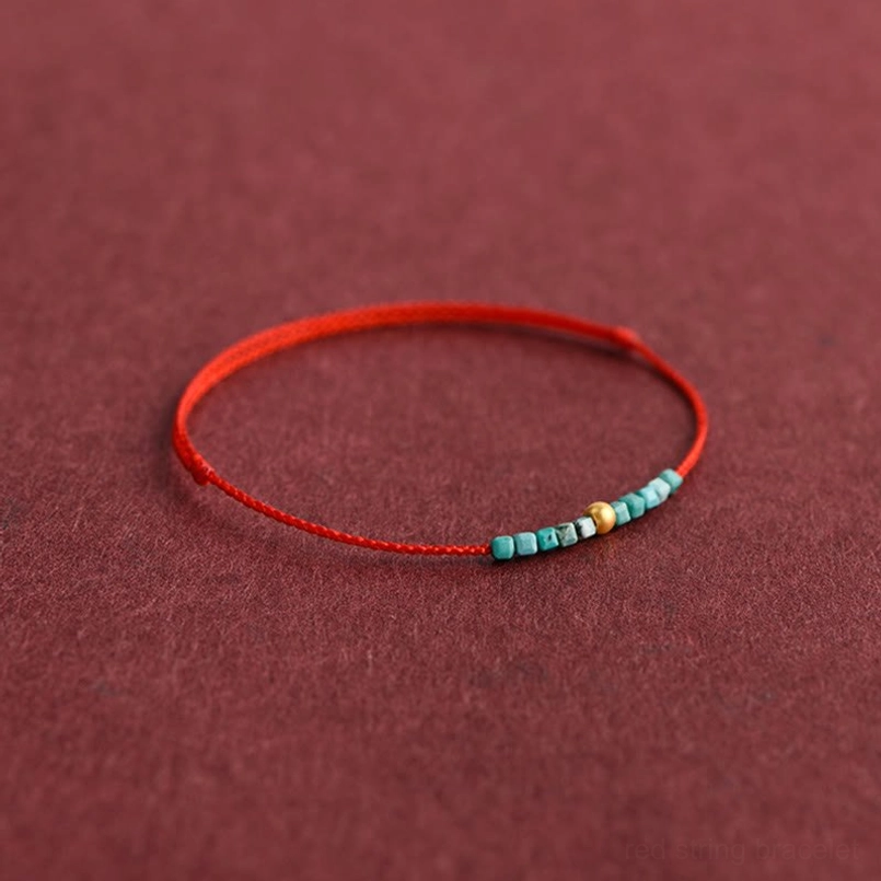 Curved red string bracelet with turquoise gold beads angled perspective display