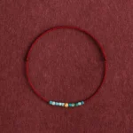 999 gold and turquoise dark red braided protection bracelet flat lay detail view