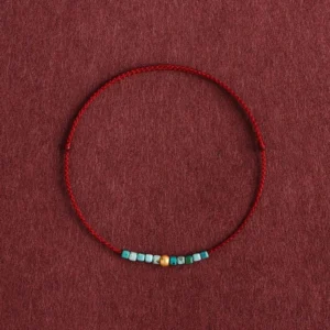 999 gold and turquoise dark red braided protection bracelet flat lay detail view