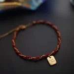 Good Luck red string bracelet oblique top down view with engraved gold copper charm