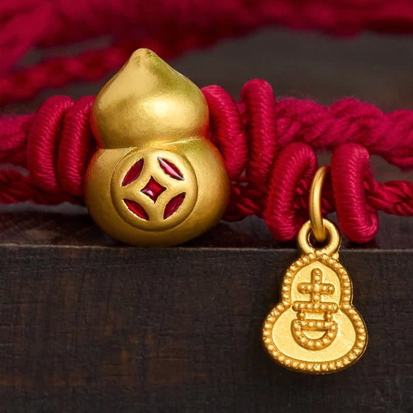 Close up of gold gourd charm with Chinese coin pattern on red string bracelet