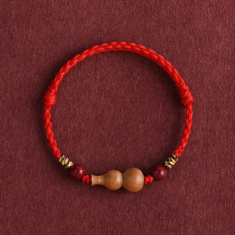 Macro close-up of dual gourd charms with cinnabar beads and colorful woven knots