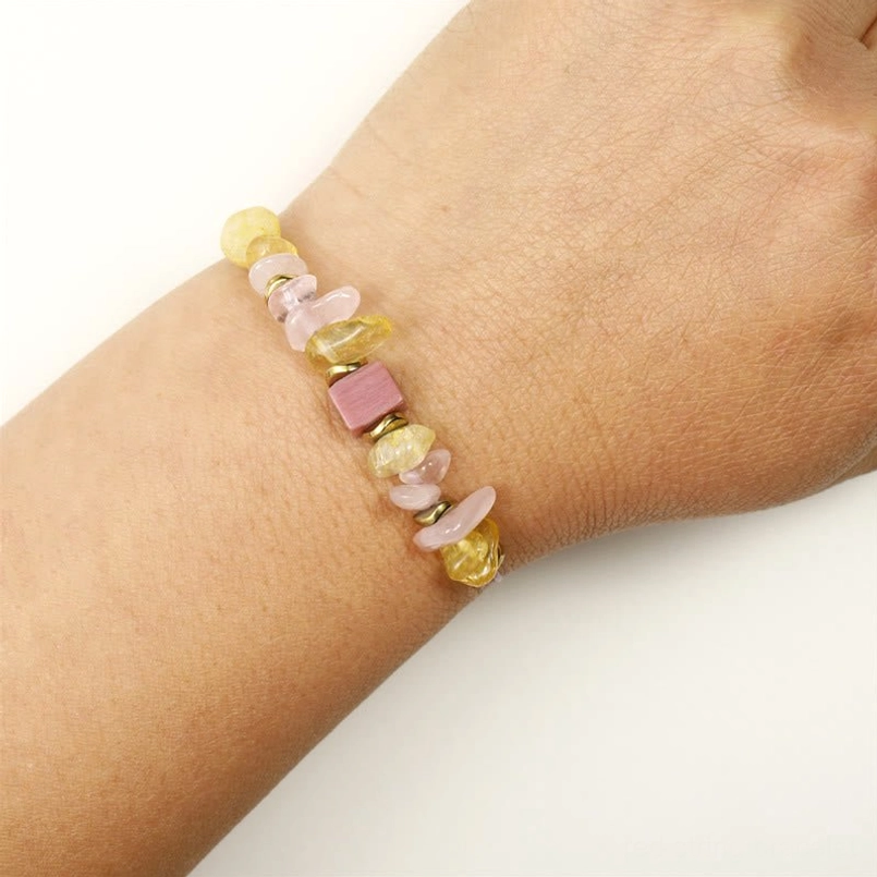 Love bracelet with rose quartz citrine beads on blue tabletop with natural props