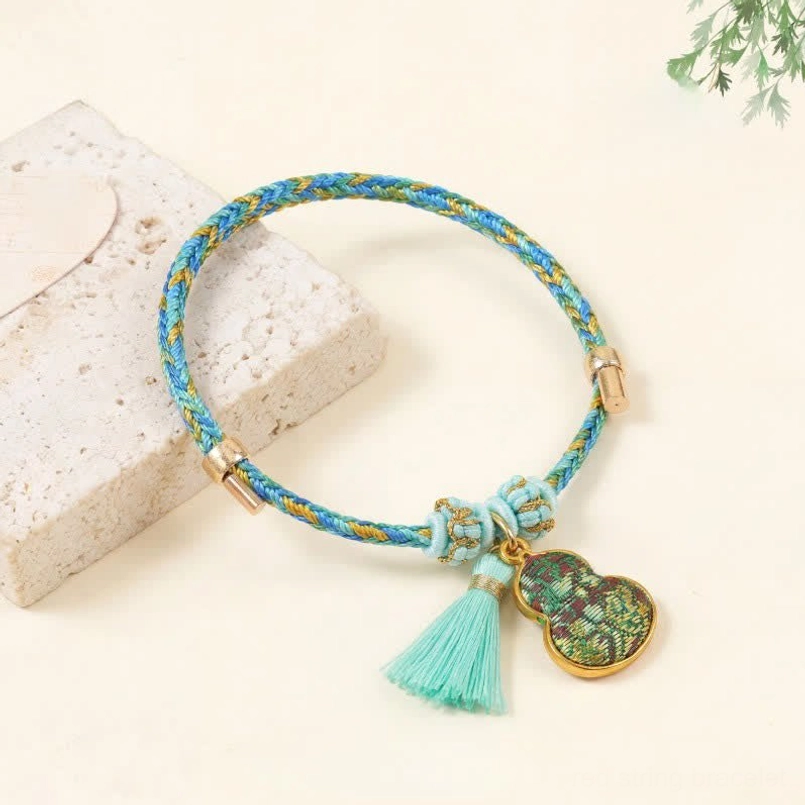 Green blue woven brocade bracelet with mint tassel dark green gourd charm and gold metal clasp side view