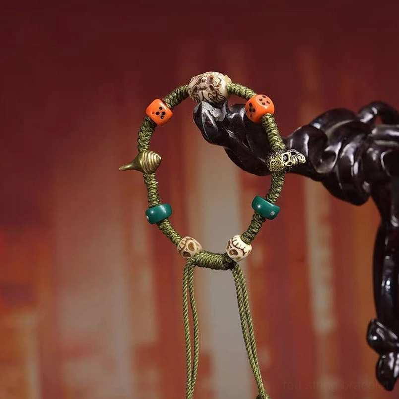 Green braided Tibetan dragon dice bracelet hanging on dark wooden display stand