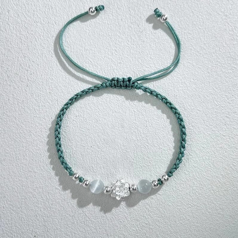 green cat's eye bead lotus red string bracelet top view on light background