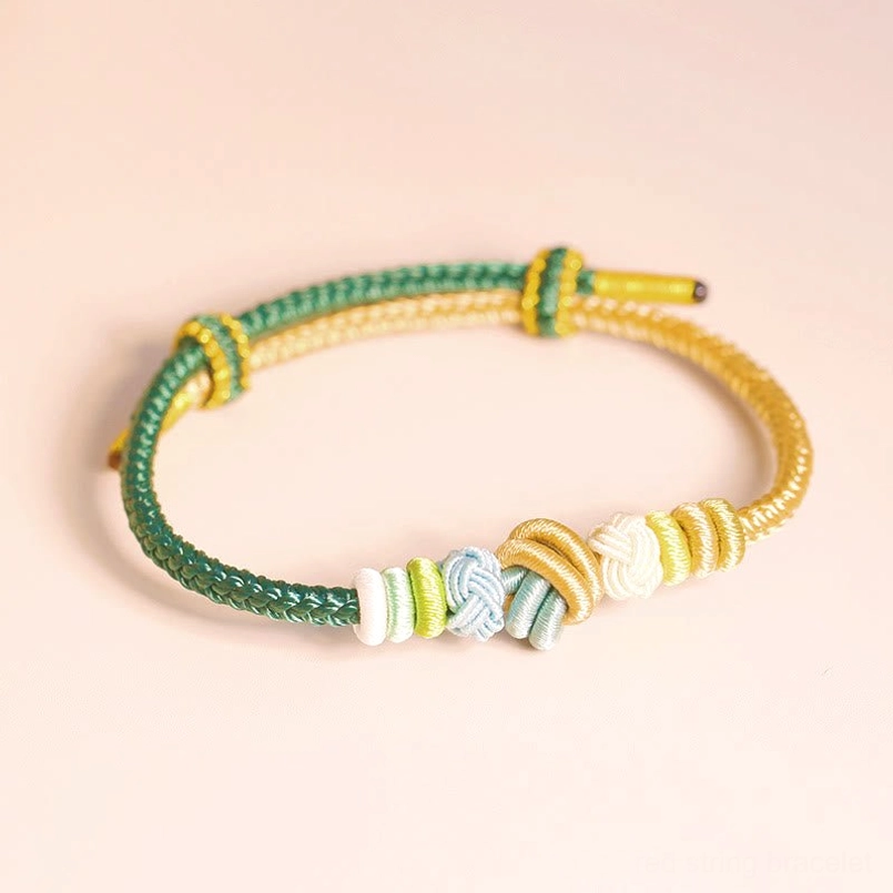 Green and gold yellow handwoven eight thread peace knot bracelet on light background showing braided texture